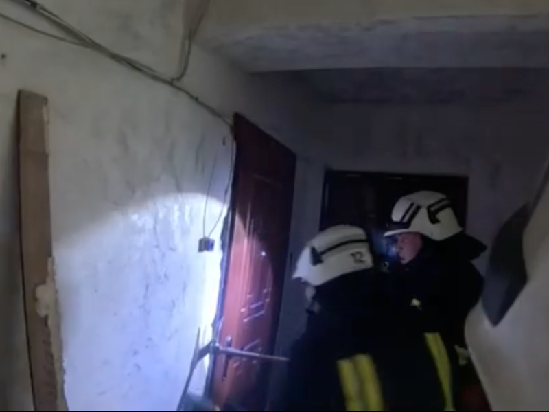 Співробітники ДСНС за допомогою шанцевого інструмента проводять аварійне розкриття вхідних металевих дверей квартири.
