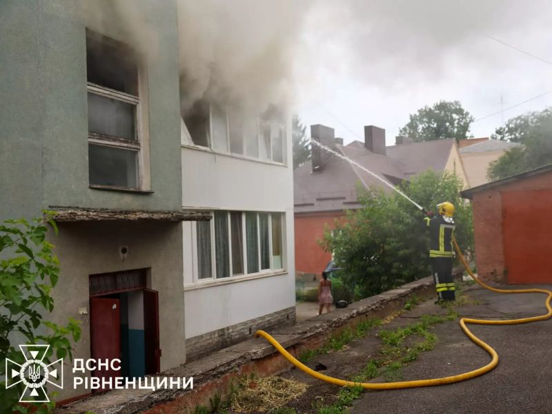Співробітник ДСНС надягає рятувальну маску на постраждалу жінку для безпечної евакуації із зони задимлення.