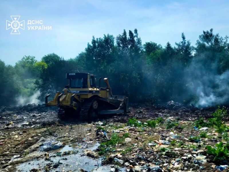 Бульдозер перекопує тліюче сміття під час ліквідації масштабної пожежі на сміттєзвалищі співробітниками ДСНС.