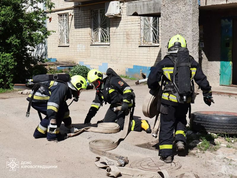 Пожежники ДСНС у бойовому одязі та дихальних апаратах готують рукавну лінію до роботи.