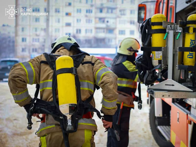 Рятувальники ДСНС у Харкові одягають дихальні апарати Dräger та захисне спорядження. Вид зі спини на вогнеборця у повному екіпіруванні перед початком гасіння пожежі в житловому районі.