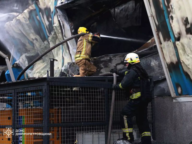 Пожежники ДСНС Дніпропетровщини подають воду з пожежного рукава в осередок загоряння через зруйновані конструкції промислової будівлі.