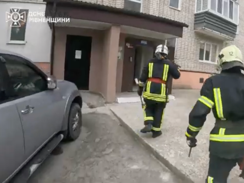 Співробітники ДСНС Рівненщини у захисному спорядженні прямують до під'їзду багатоквартирного будинку для ліквідації надзвичайної ситуації.