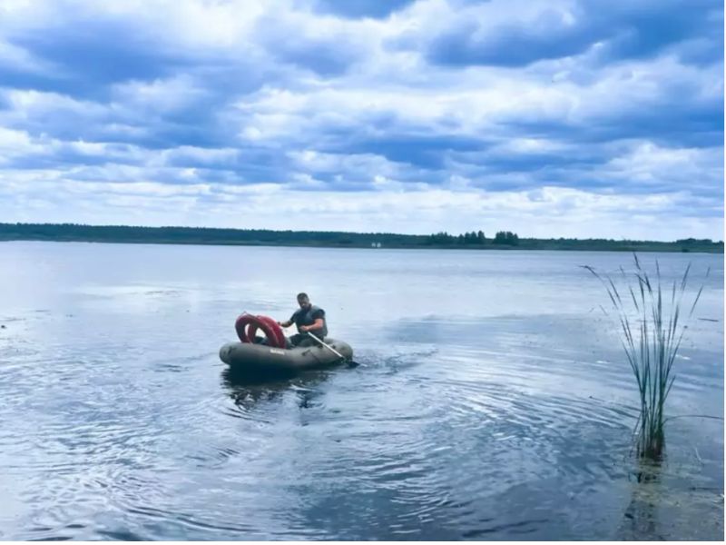 Співробітник ДСНС у рятувальному жилеті гребе на надувному човні з рятувальними колами під час операції з порятунку підлітків на озері у м. Соснівка.