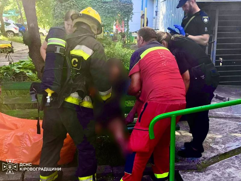 Рятувальник ДСНС, медики екстреної допомоги та поліція надають першу медичну допомогу врятованому чоловіку після пожежі у Світловодську.