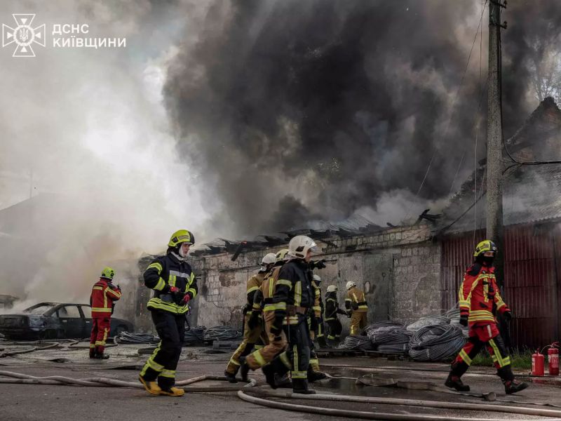 Підрозділ ДСНС розгортає пожежні рукави для гасіння масштабного займання складського приміщення на Київщині.